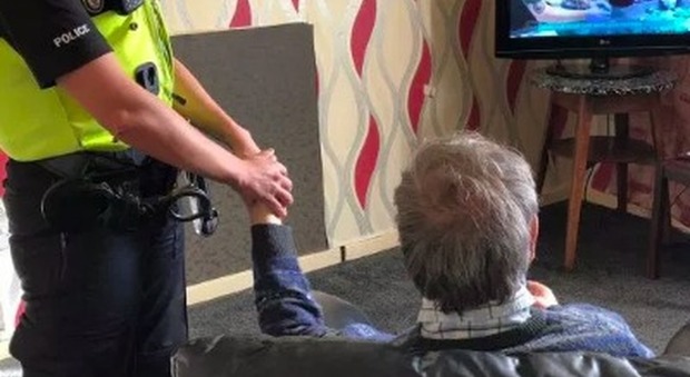 Poliziotta tiene la mano dell'anziano rimasto vedovo, il motivo vi scalderà il cuore. La foto fa il giro del web