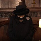 Elisabetta in abito nero, un po' curva e  con una spilla speciale